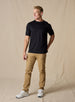 Men's Luxe Tee in Black, on model full body front view featuring a black short sleeve crew neck tee paired with tan pants and white shoes