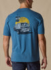 Vegas Vacation Graphic Tee in Petrol, back model view featuring a heathered blue short-sleeve crewneck tee with a vintage-style graphic of a classic woody wagon loaded with golf clubs in front of a golden sun and retro roadside, paired with navy pants
