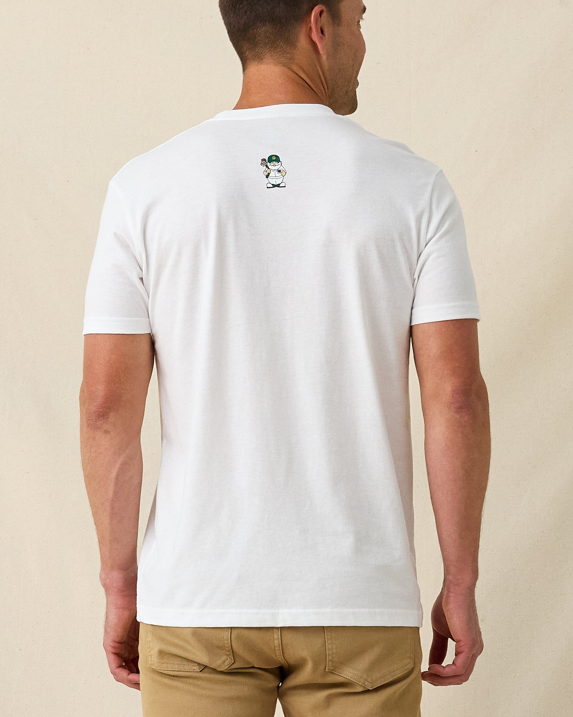 Men's IYKYK Tee in White, back view on model featuring a white base with a small golf gnome character graphic at upper back, paired with khaki pants