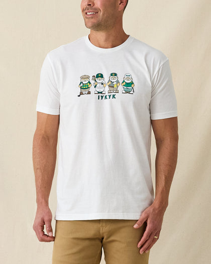 Men's IYKYK Tee in White, front view on model featuring a white base with a four golf gnome character graphic and IYKYK text in green on the chest, paired with khaki pants