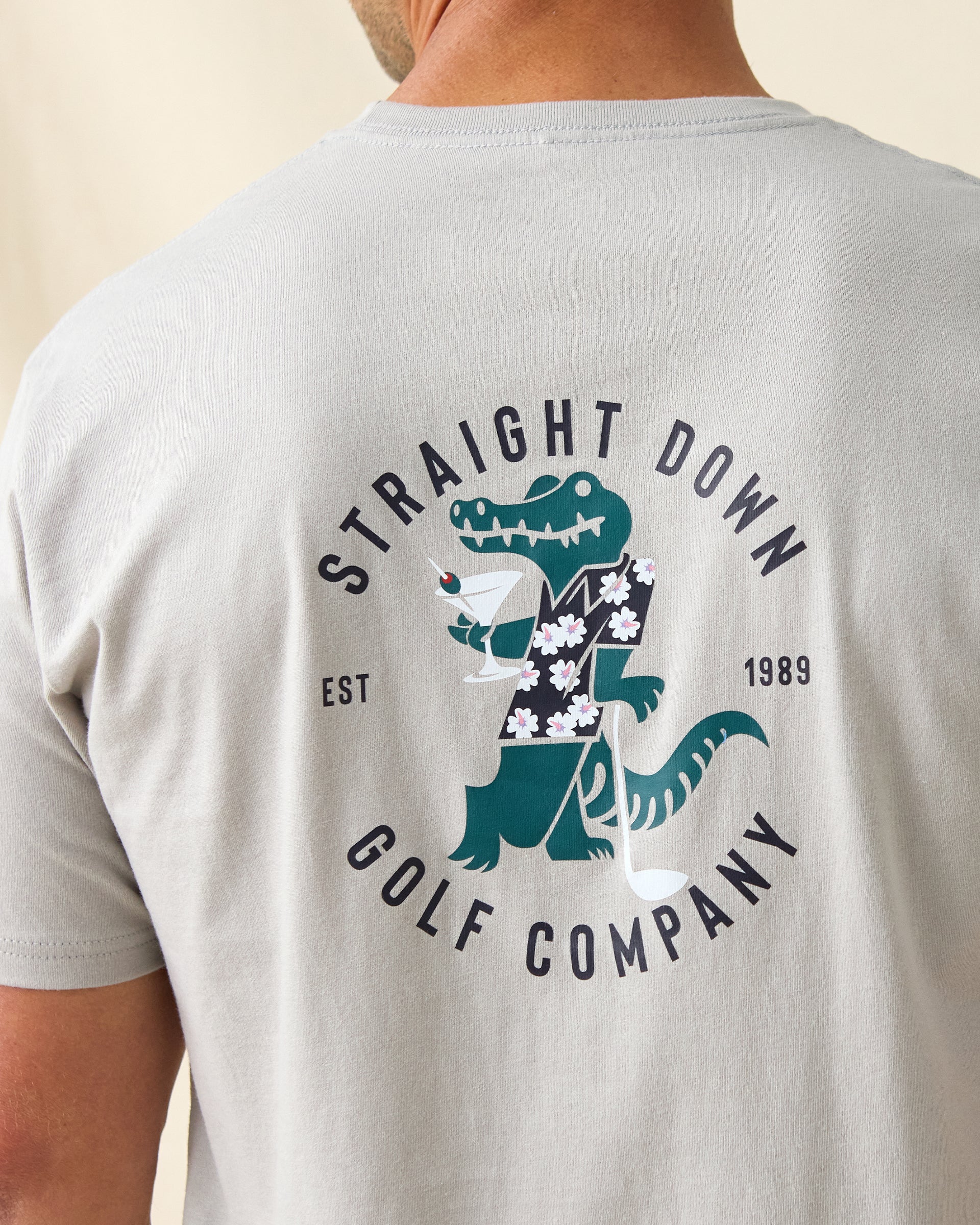 Men's Alligator Alley Tee in Light Grey, close-up back model view featuring the large Straight Down Golf Company Est. 1989 alligator graphic detail