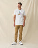 Men's Munch Tee in White, full length front view on model featuring a white base with a pimento cheese sandwich and iced drink graphic with MUNCH text on the chest, paired with khaki pants and white shoes