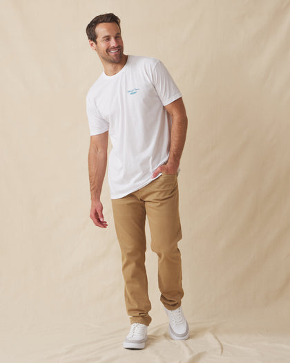 Men's Island Time Tee in White, full-length front view on model featuring a white crew neck tee with small blue Straight Down logo graphic, styled with khaki pants and white shoes