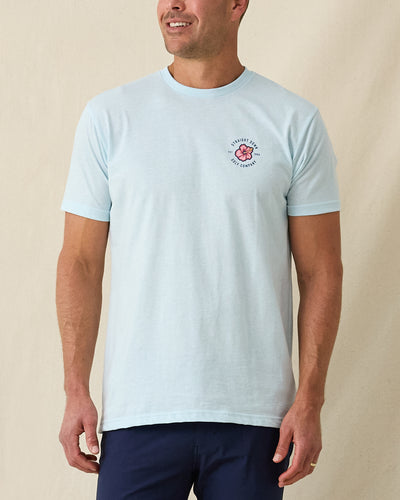 Men's Hibiscus 89 Tee in Light Blue, front view on model featuring the Straight Down Golf Company hibiscus logo on the left chest, paired with navy pants