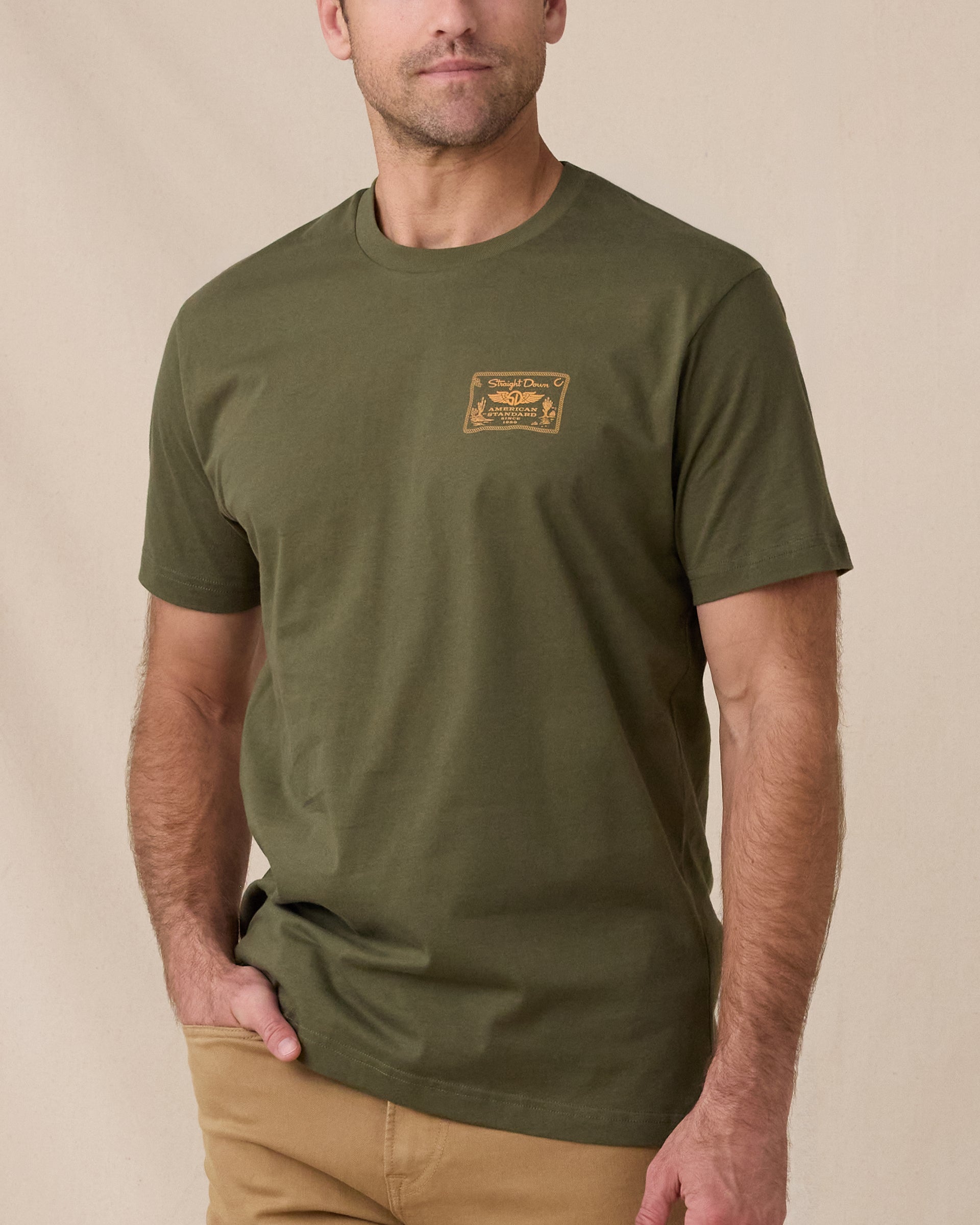 Man wearing the American Standard Tee in Army Green with a small gold graphic on the left chest.
