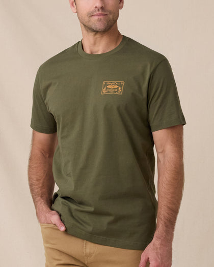 Man wearing the American Standard Tee in Army Green with a small gold graphic on the left chest.