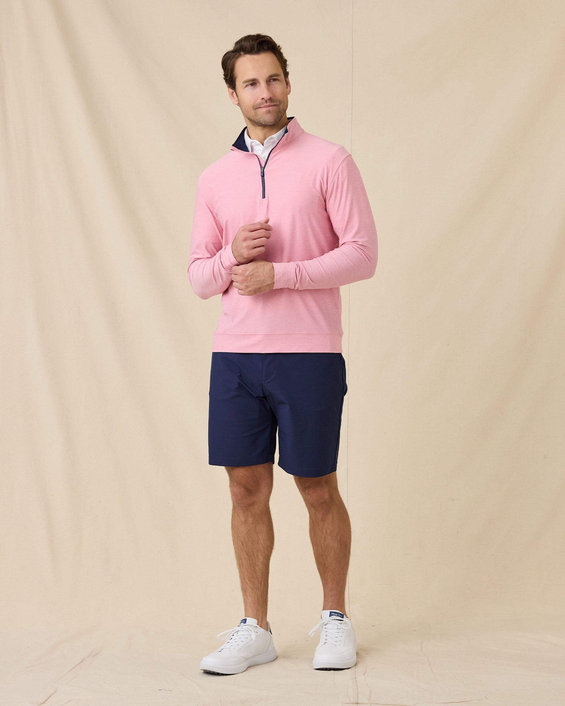 Model wearing the Oceanside 2.0 Quarter Zip in Punch Pink with navy golf shorts