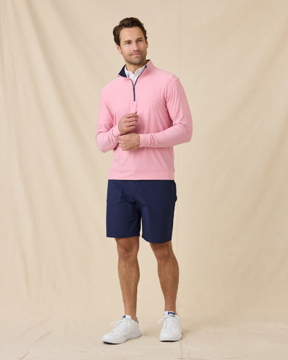 Model wearing the Oceanside 2.0 Quarter Zip in Punch Pink with navy golf shorts