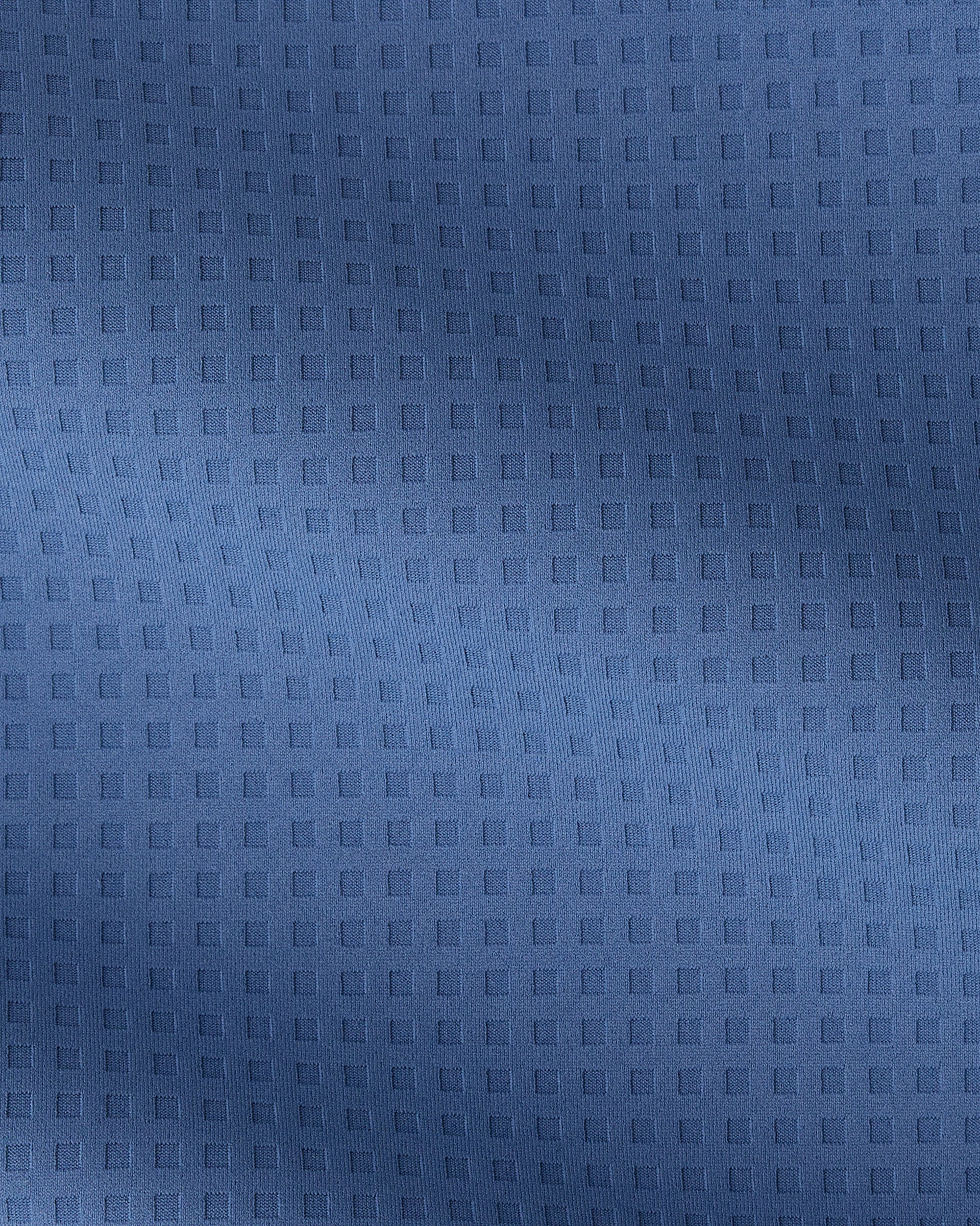 A close-up of a textured blue fabric with a repeating embossed square grid pattern.