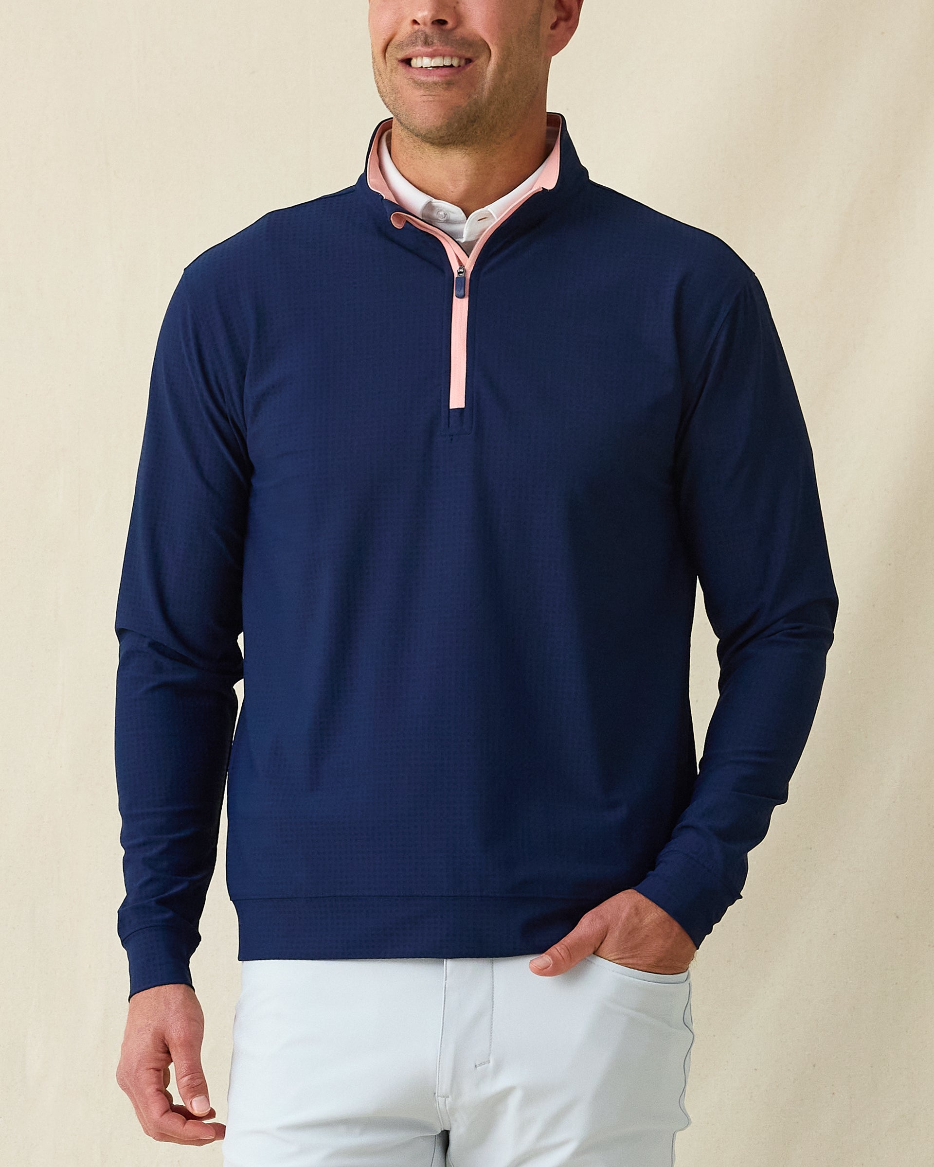 Men's Bel Air Quarter Zip in New Indigo, front model view featuring a navy long sleeve quarter zip pullover with a subtle textured fabric and pink contrast zip placket, layered over a white striped polo, styled with light gray pants