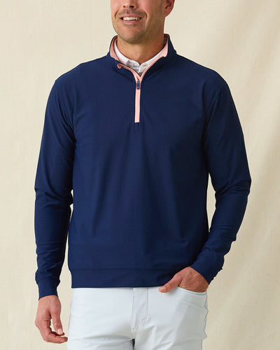Men's Bel Air Quarter Zip in New Indigo, front model view featuring a navy long sleeve quarter zip pullover with a subtle textured fabric and pink contrast zip placket, layered over a white striped polo, styled with light gray pants