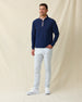 Men's Bel Air Quarter Zip in New Indigo, full length model view featuring a navy long sleeve quarter zip pullover with a subtle textured fabric and pink contrast zip placket, layered over a white striped polo, styled with light gray pants and white shoes