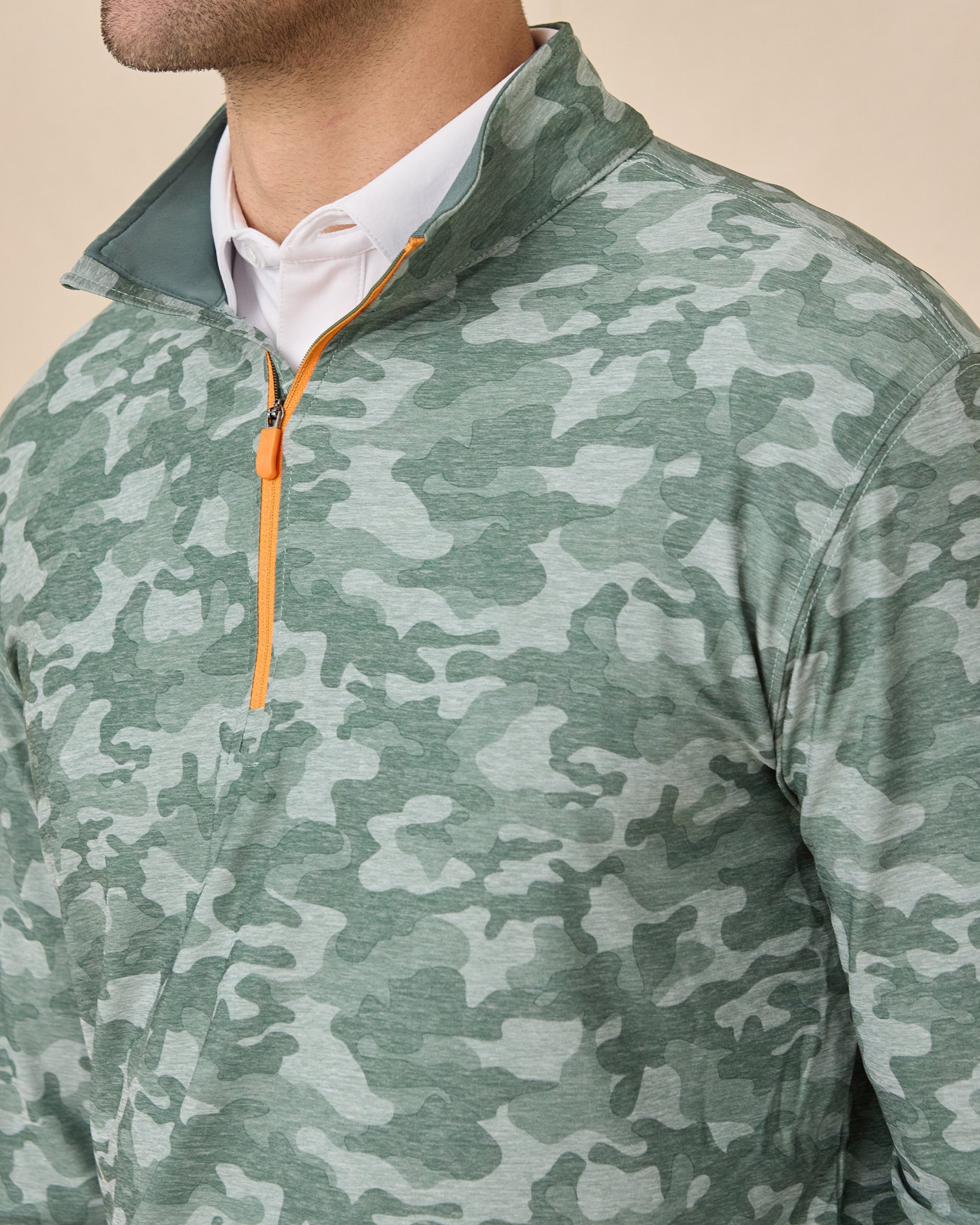 Close-up of the Arlington Quarter Zip in Dark Forest highlighting the camouflage print, stand collar, and contrasting orange zipper.