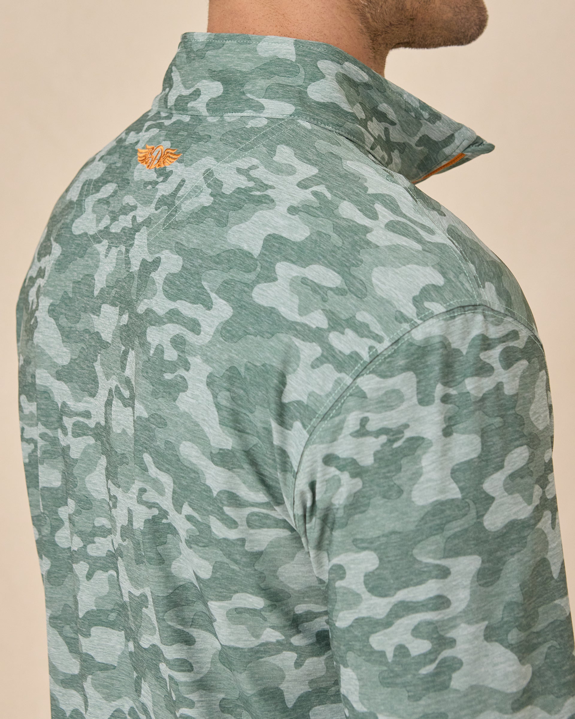 Close-up of the Arlington Quarter Zip in Dark Forest showing the camouflage print and orange embroidered logo below the collar.