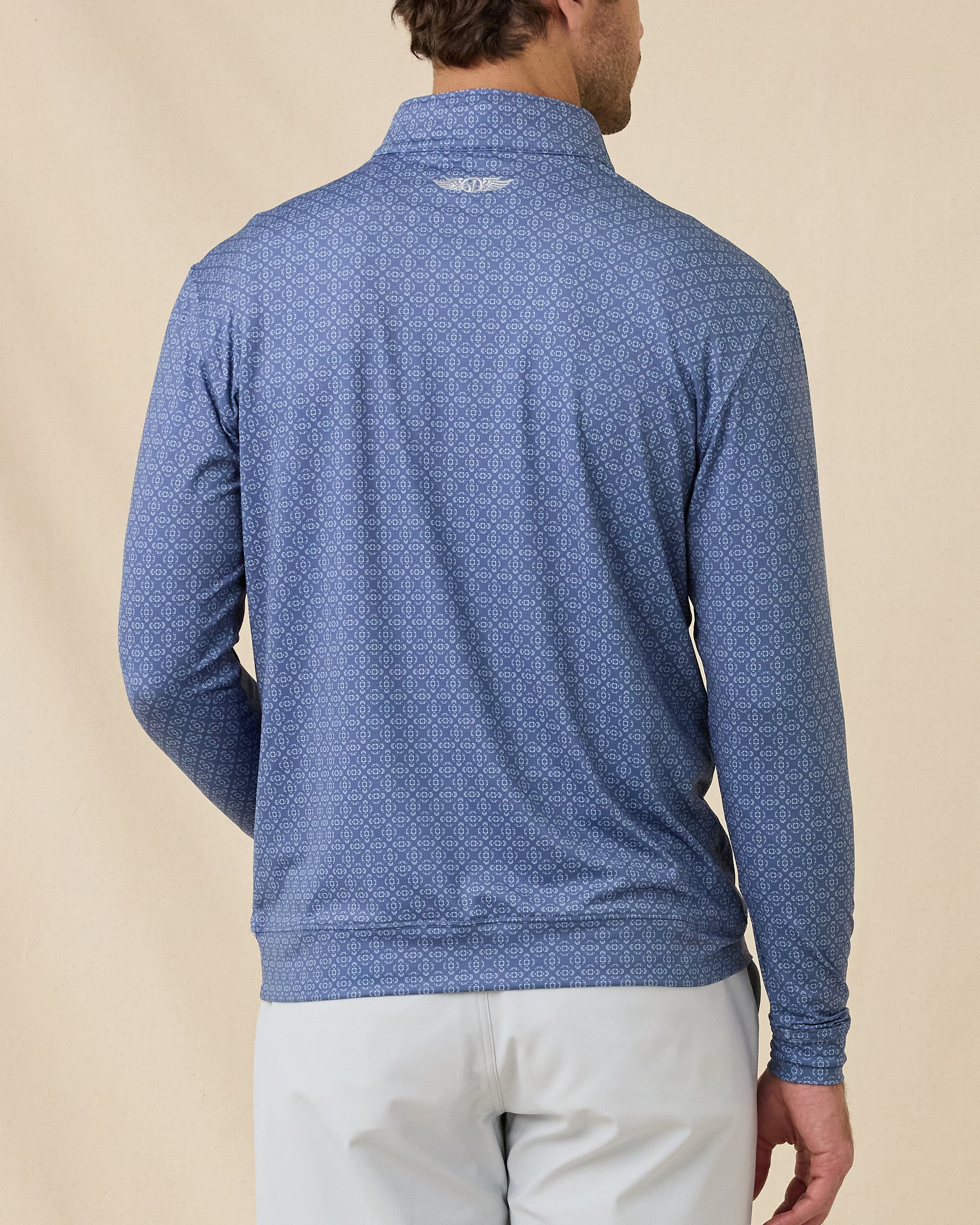 Back view of a man wearing the Mulholland Quarter Zip in Moonlight, showing the allover geometric print and embroidered logo below the back collar.
