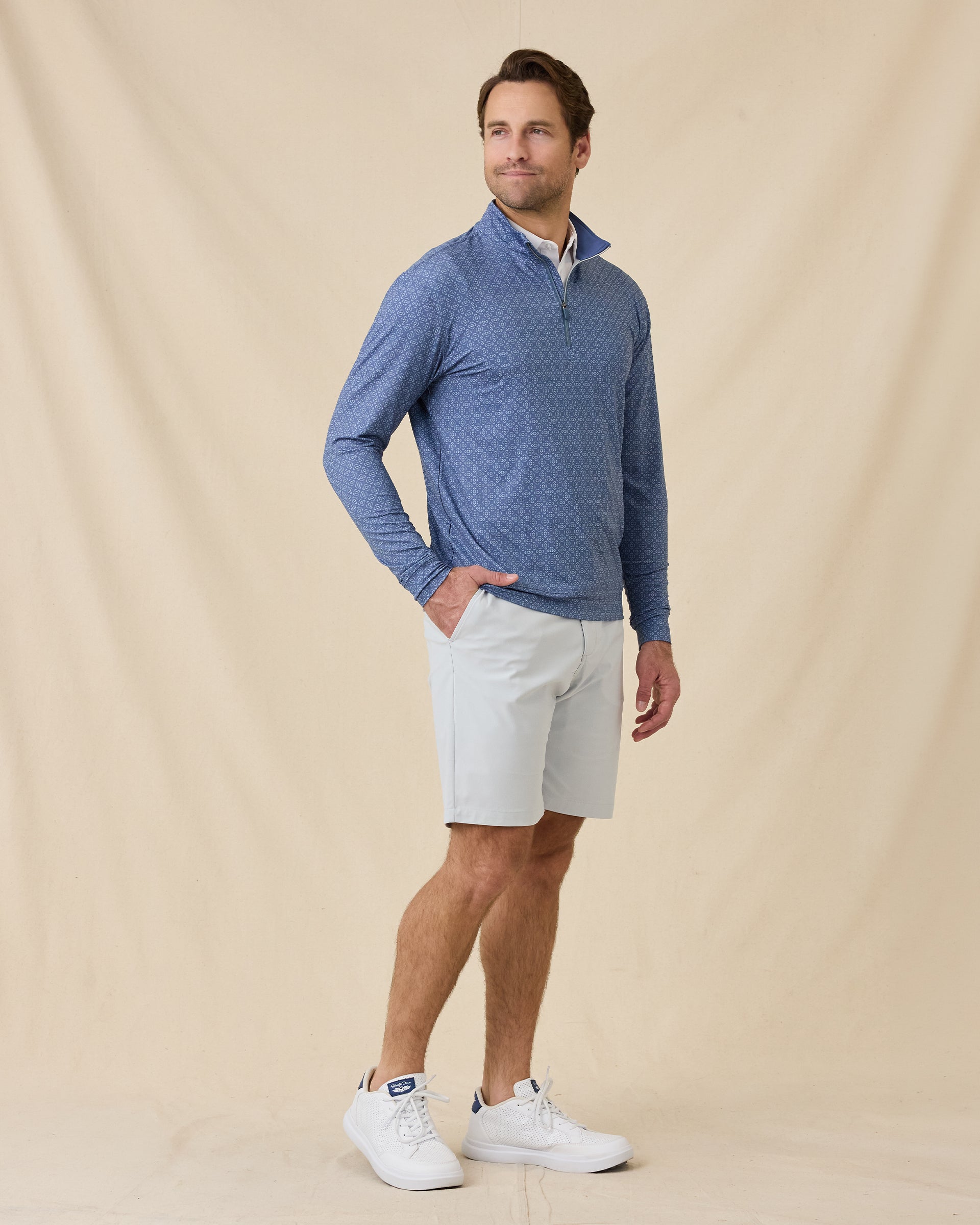 Full-length view of a man wearing the Mulholland Quarter Zip in Moonlight with light gray shorts and white golf shoes.