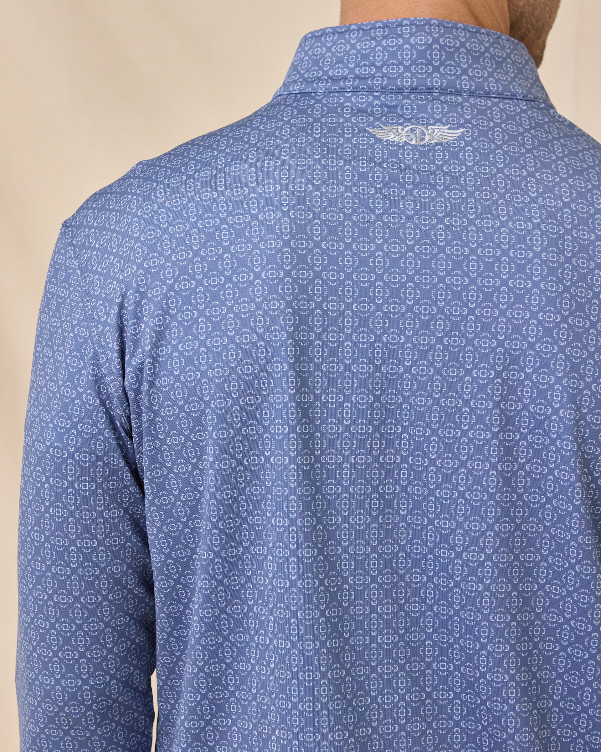 Close-up back view of the Mulholland Quarter Zip in Moonlight showing the geometric print and embroidered logo below the collar.