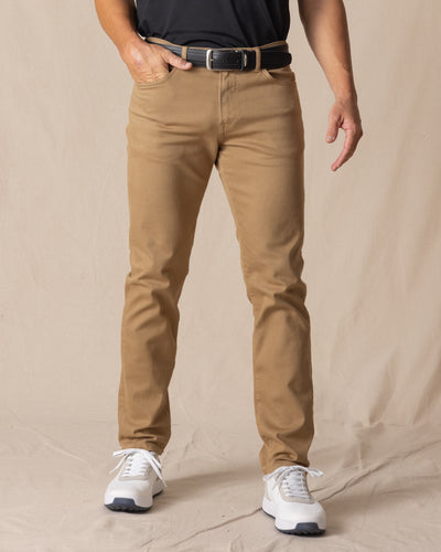 Men's Claremont Five Pocket Twill Pant in British Khaki, front on-model view featuring a warm tan twill fabric, styled with a black t-shirt, black leather belt, and white shoes