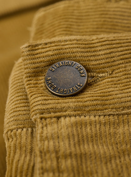 Men's Smithson Corduroy Pant in Bronze, close-up detail view of the antiqued brass Straight Down branded button against the golden tan fine wale corduroy fabric
