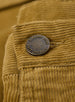 Men's Smithson Corduroy Pant in Bronze, close-up detail view of the antiqued brass Straight Down branded button against the golden tan fine wale corduroy fabric