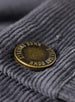 Men's Smithson Corduroy Pant in Walrus, close-up detail view of the antiqued brass Straight Down branded button against the charcoal gray fine wale corduroy fabric