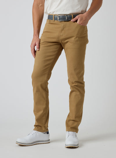 Men's Henderson 5 Pocket Pant in Bronze, front model view featuring a five-pocket silhouette styled with a navy belt and white golf shoes