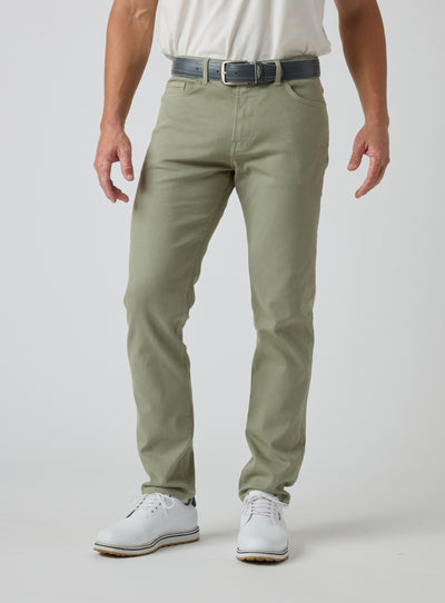 Men's Henderson 5 Pocket Pant in Moss, front model view featuring a five-pocket silhouette styled with a navy belt and white golf shoes