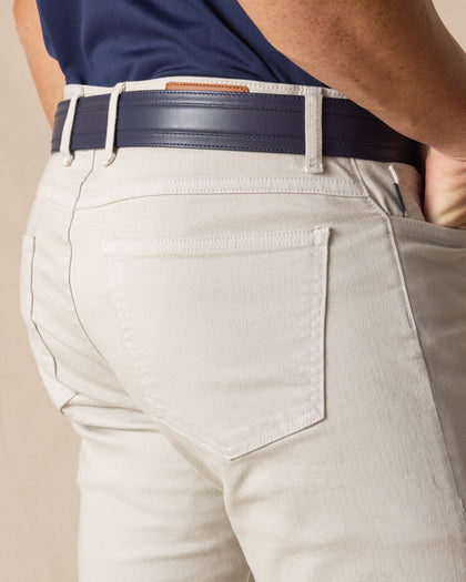 Men's Henderson 5 Pocket Pant in Stone, close-up back pocket detail featuring tonal topstitching and clean construction in a warm off-white colorway, styled with a navy leather belt