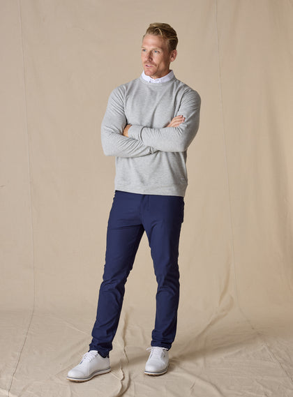 Men's Nathan 2.0 Crew in Light Grey Heather, full-length front view on male model with arms crossed, styled with navy pants and white golf shoes against a neutral linen backdrop