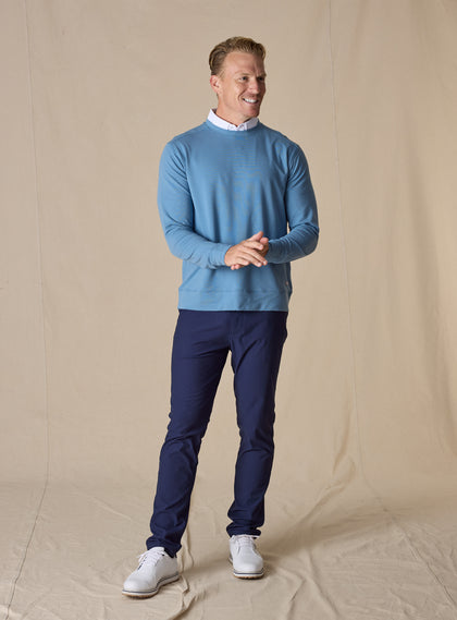Men's Nathan 2.0 Crew in Petrol, full-length front view on male model styled with navy pants and white golf shoes against a neutral linen backdrop