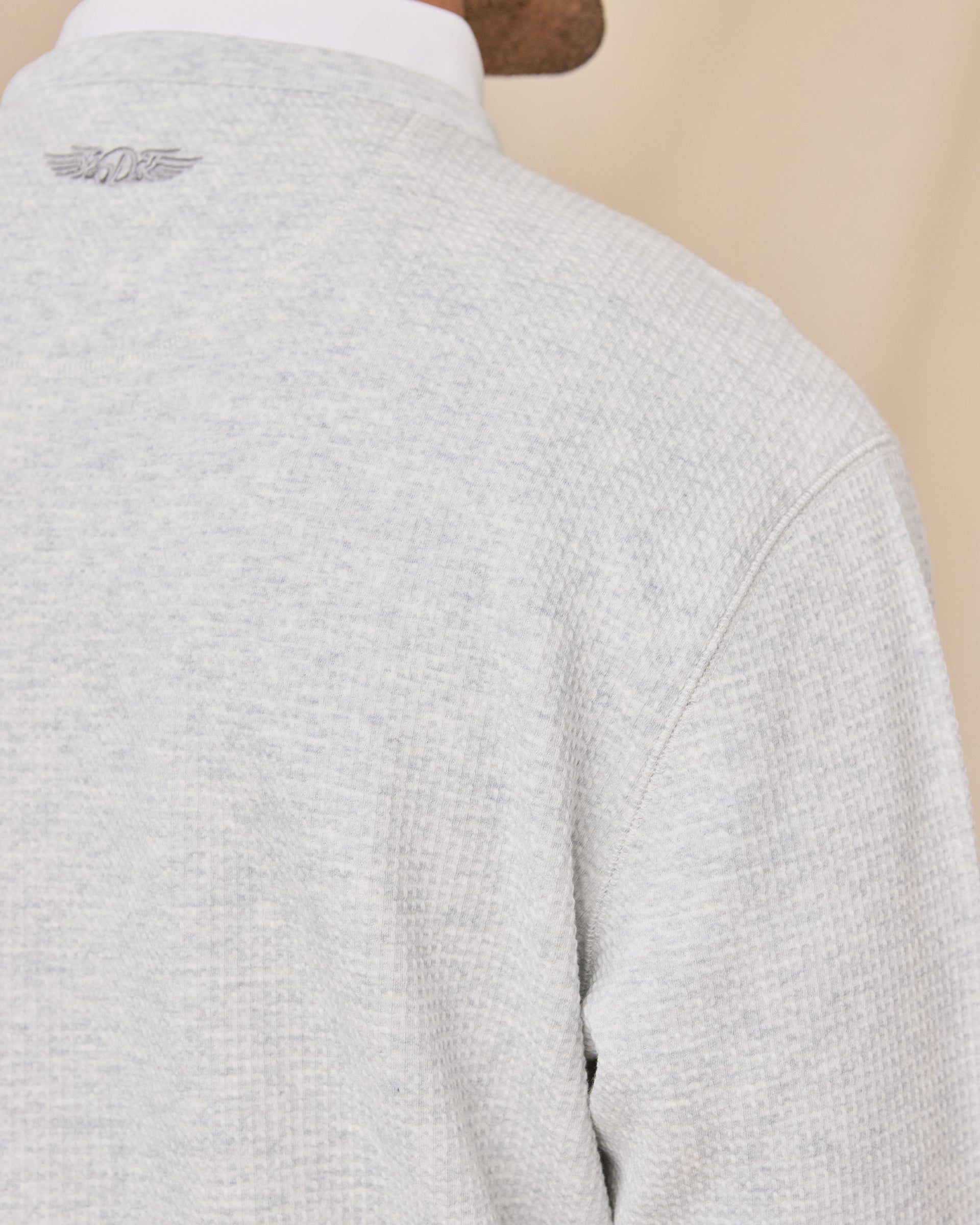 Close-up of the Hopkins Crew in Heather highlighting the textured knit, shoulder seam, and embroidered logo below the neckline.