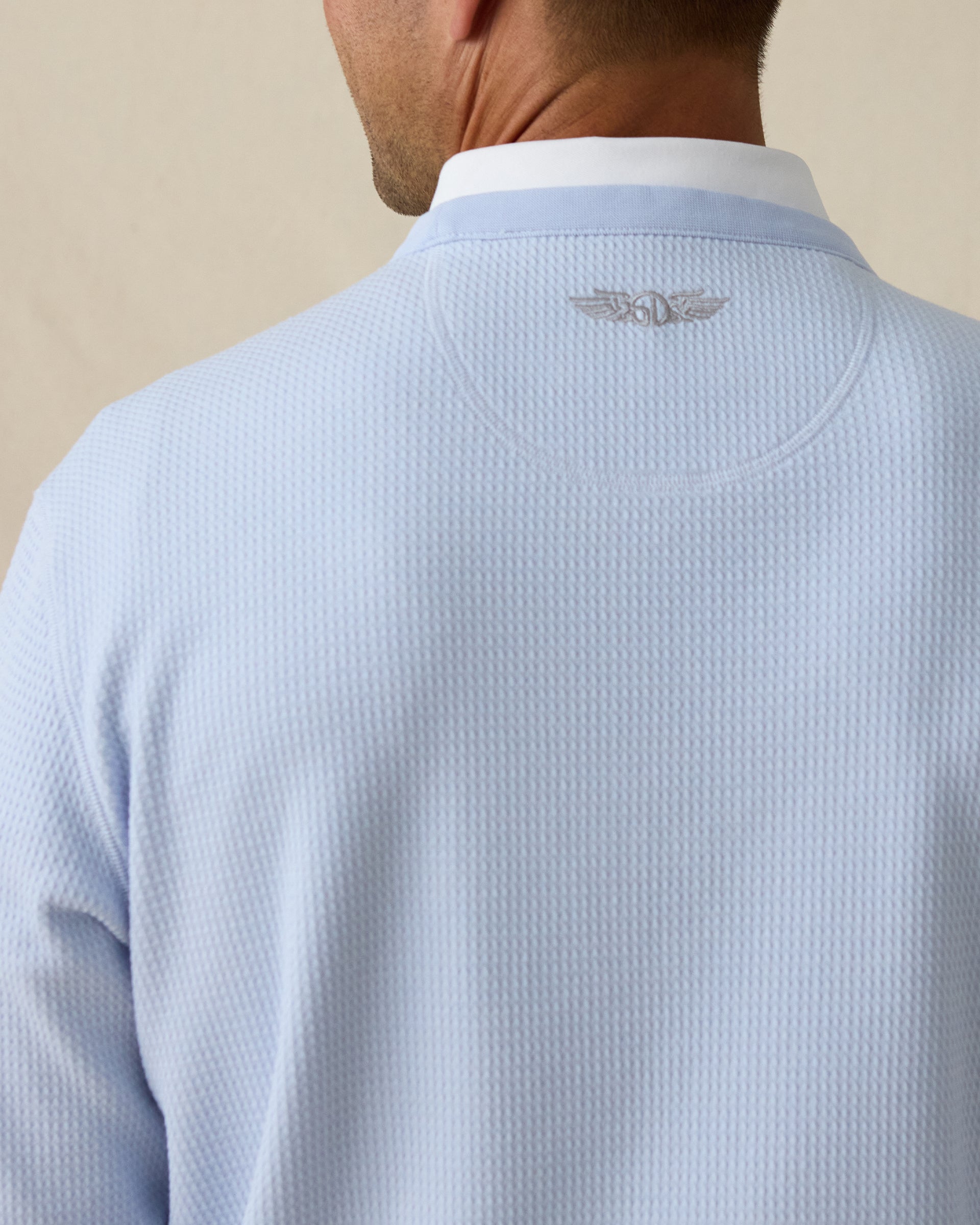 Close-up of back neck showing subtle embroidered Straight Down winged logo on light blue pullover.