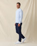 Men’s light blue crewneck pullover styled with navy pants and white sneakers in a clean golf outfit.