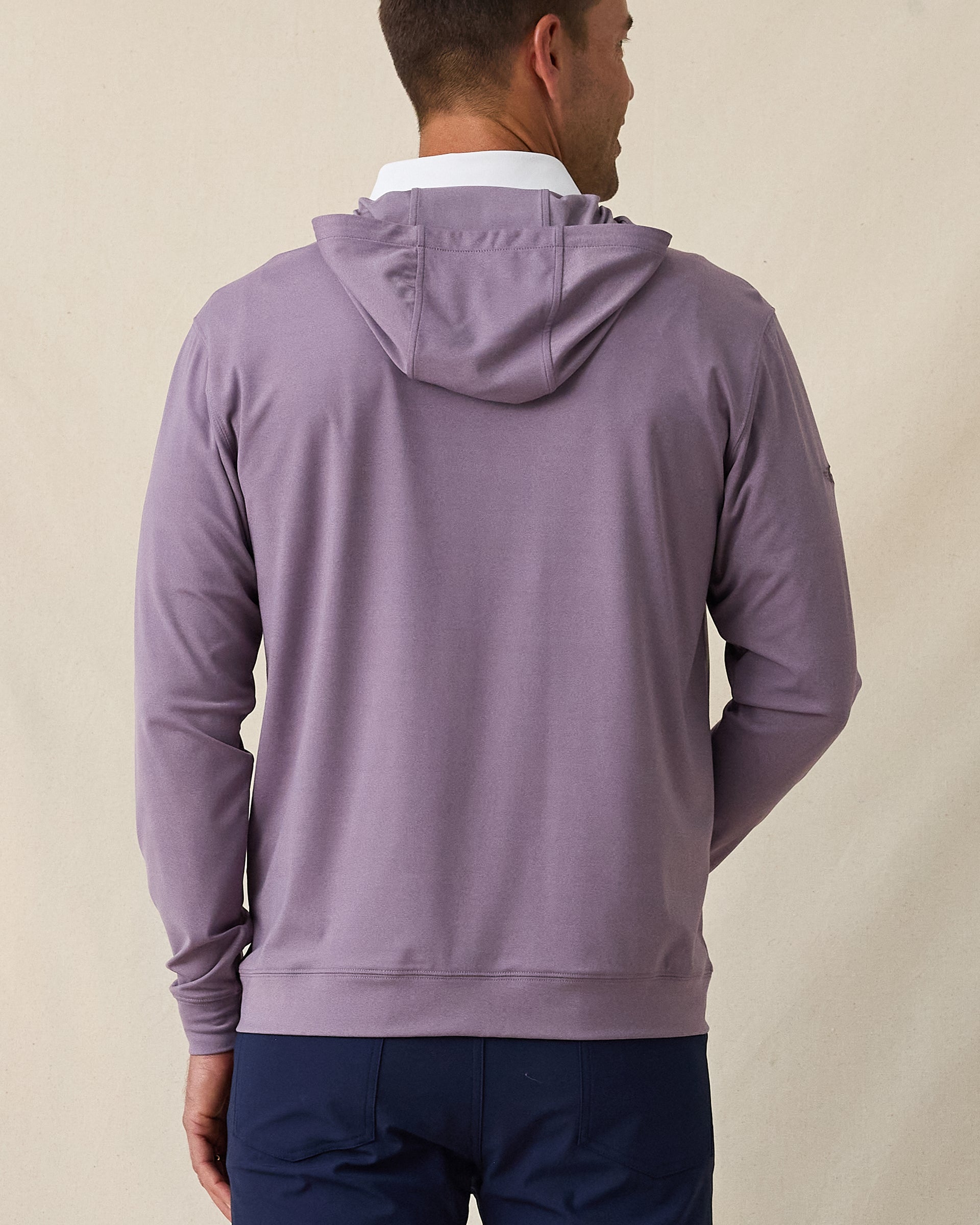 Back of man wearing purple pullover hoodie over a white polo styled with navy pants