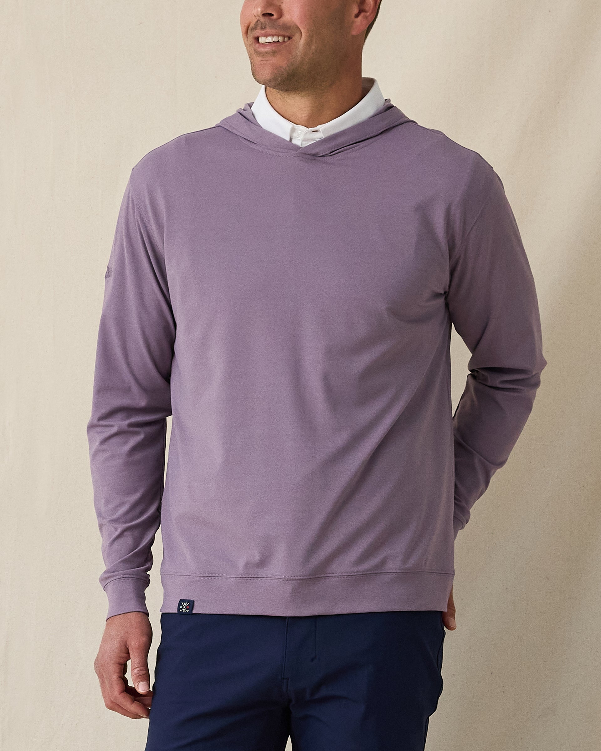 Man wearing purple pullover hoodie over a white polo styled with navy pants