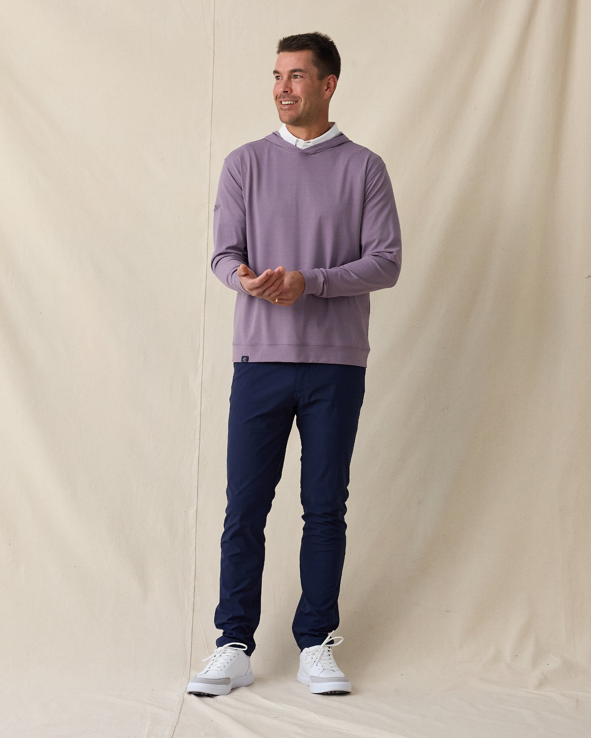 Man wearing purple pullover hoodie over a white polo styled with navy pants and white shoes