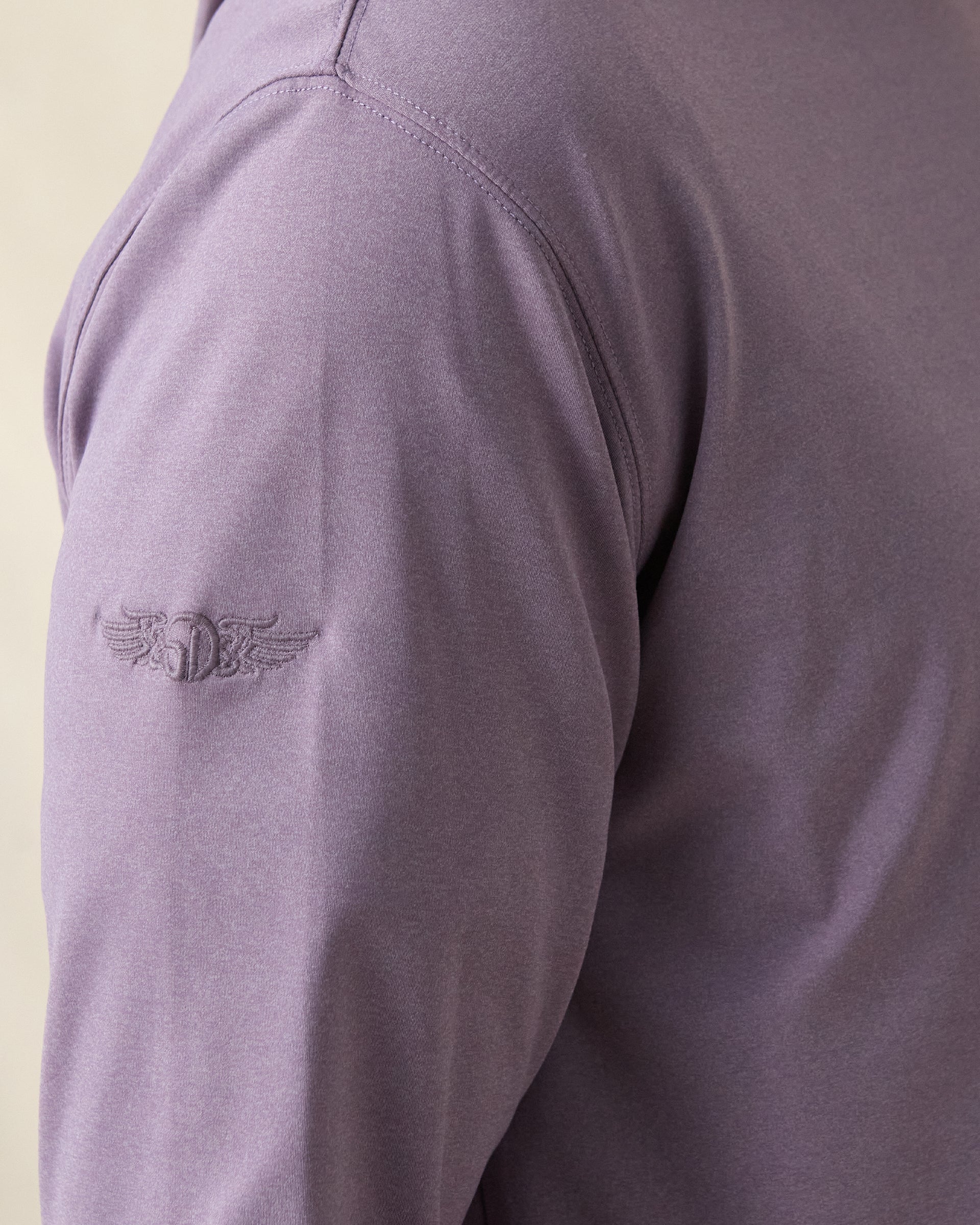 Close-up of a purple long-sleeve shirt with a purple logo on the sleeve