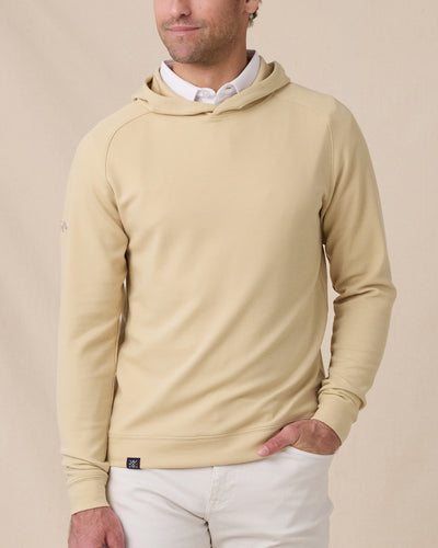 Front view of a model wearing the Gridlock Hoodie in Sandstorm layered over a white polo with white pants.
