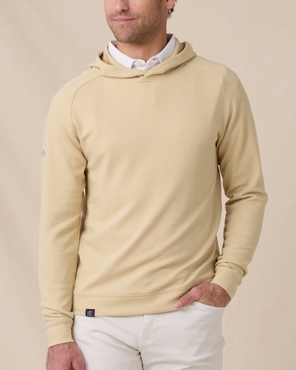Front view of a model wearing the Gridlock Hoodie in Sandstorm layered over a white polo with white pants.