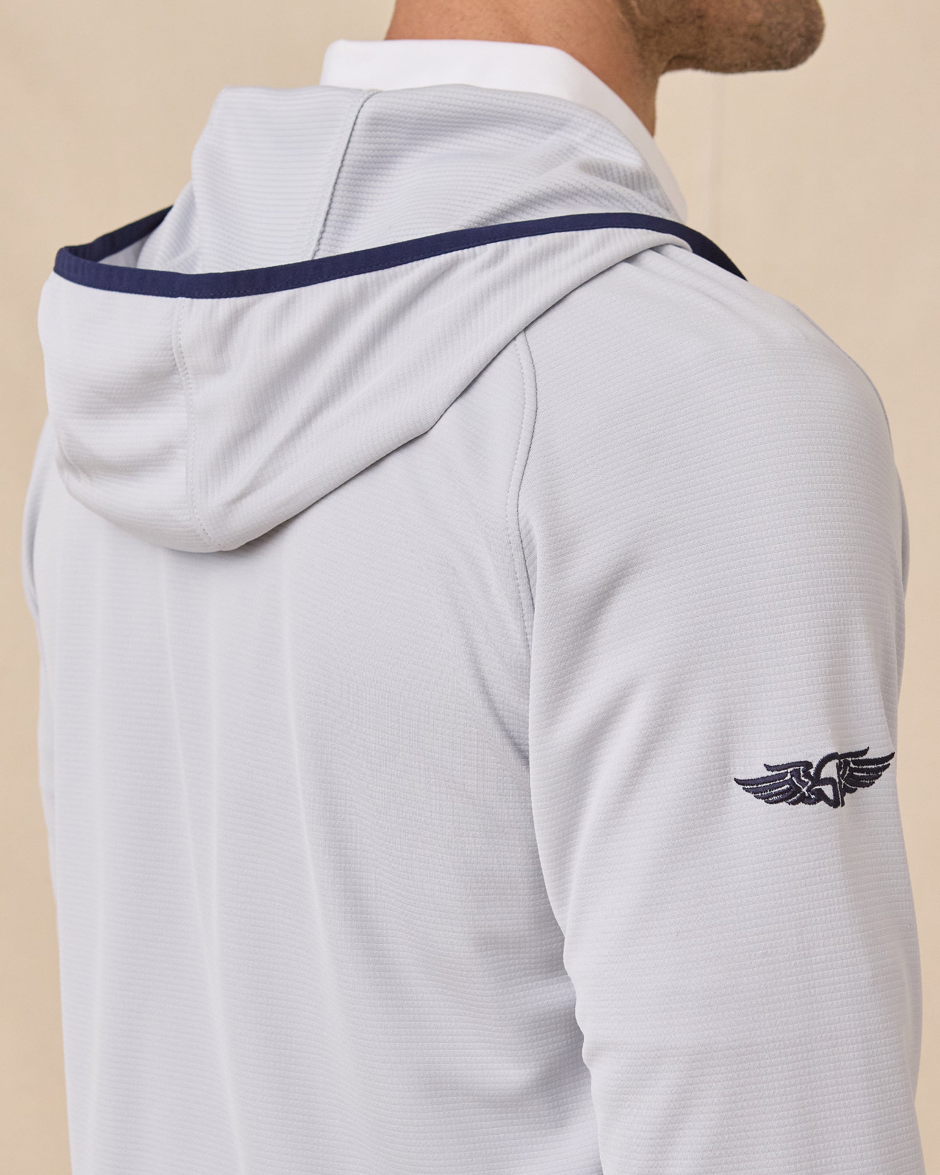 Close-up back view of the Condor Full Zip Hoodie in Silver showing the hood construction, navy trim, and embroidered sleeve logo
