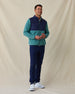 Men's Okemo Hybrid Fleece Jacket in Sage, full length front view on model featuring a navy quilted upper body with a sage fleece lower body and sleeves, paired with navy pants and white shoes