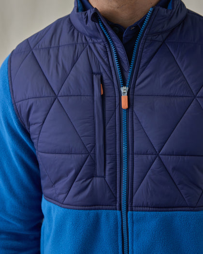 Men's Okemo Hybrid Fleece Jacket in Bering, close-up front view featuring the navy quilted diamond upper body with an orange-accented chest zip pocket and full zip closure detail