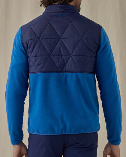 Men's Okemo Hybrid Fleece Jacket in Bering, back view on model featuring a navy quilted upper back with royal blue fleece lower body and sleeves with the Straight Down logo embroidered at the upper back, worn with navy pants
