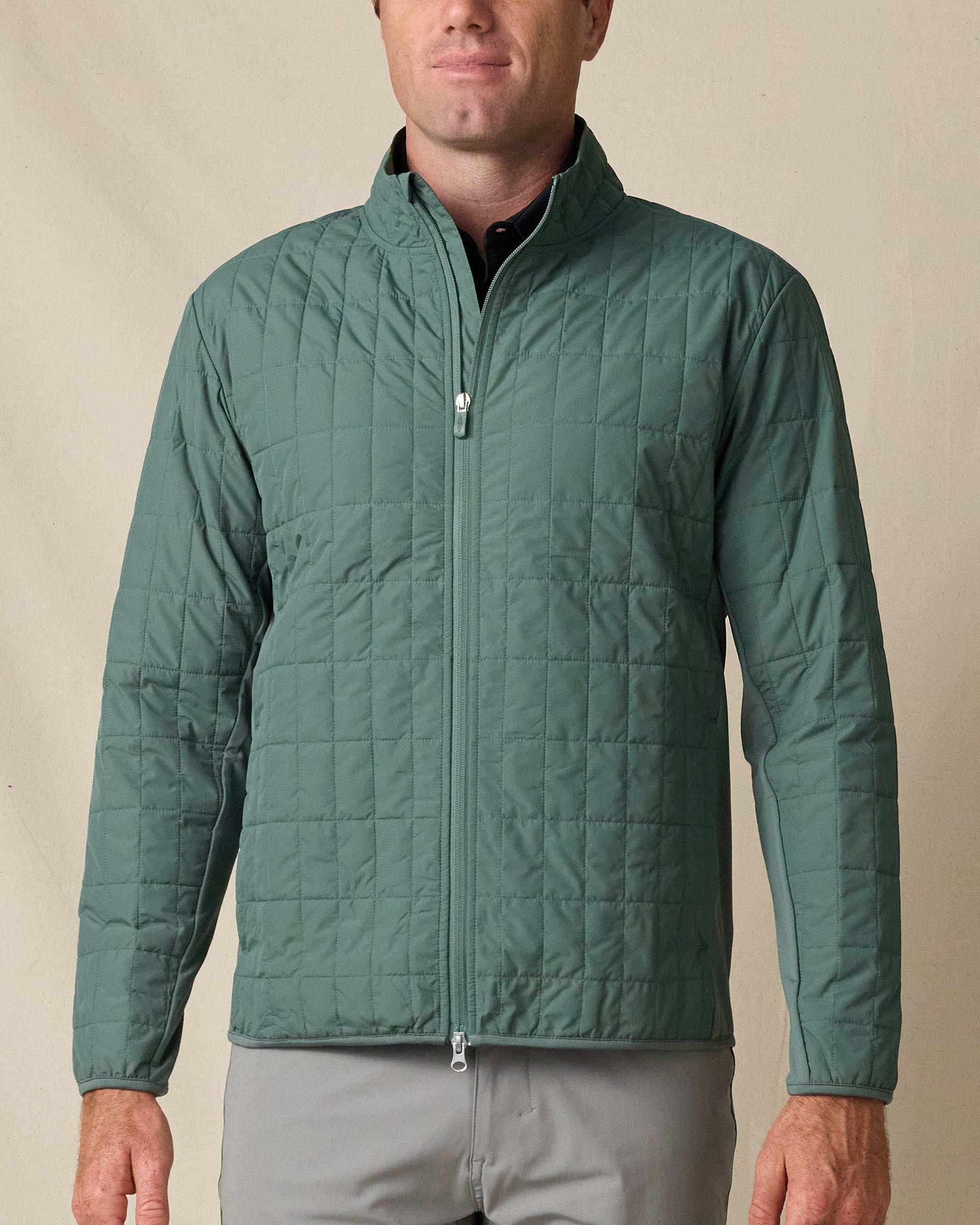 Model wearing the Big Sky Quilted Jacket in Dark Forest, featuring grid quilting, a full-zip front, and stand collar.