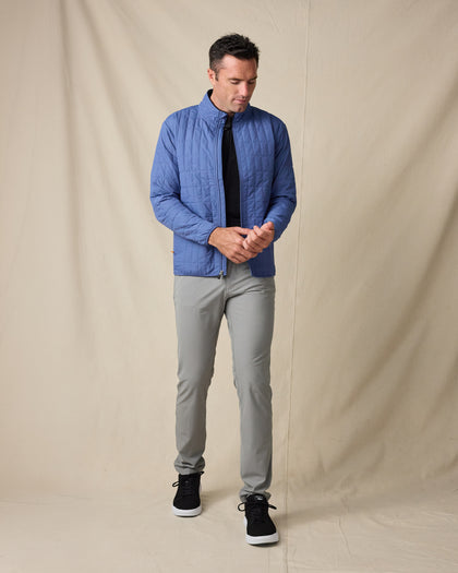 Model wearing the Big Sky Quilted Jacket in Moonlight with a black polo, gray pants, and black sneakers.