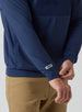 Men's Harding Hybrid Quarter Zip in New Indigo, close-up detail of logo patch at hem and dual-fabric paneling with side pocket