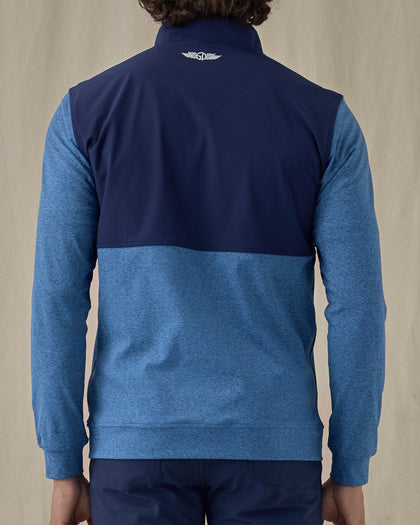 Men's Harding Hybrid Quarter Zip in Bering, back view on model featuring a navy performance upper back with a heathered blue fleece lower body and sleeves with the Straight Down logo embroidered at the upper back, worn with navy pants