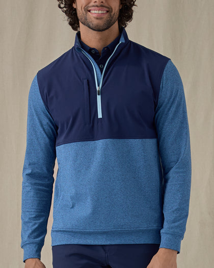 Men's Harding Hybrid Quarter Zip in Bering, front view on model featuring a navy performance upper body with a heathered blue fleece lower body and sleeves with a light blue quarter zip, layered over a navy polo, worn with navy pants