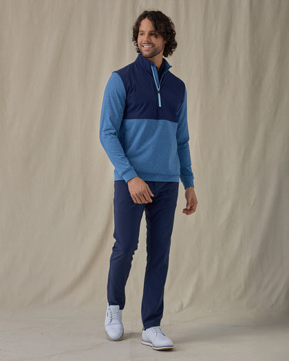 Men's Harding Hybrid Quarter Zip in Bering, full front view on model featuring a navy performance upper body with a heathered blue fleece lower body and sleeves, worn with navy pants and white golf shoes