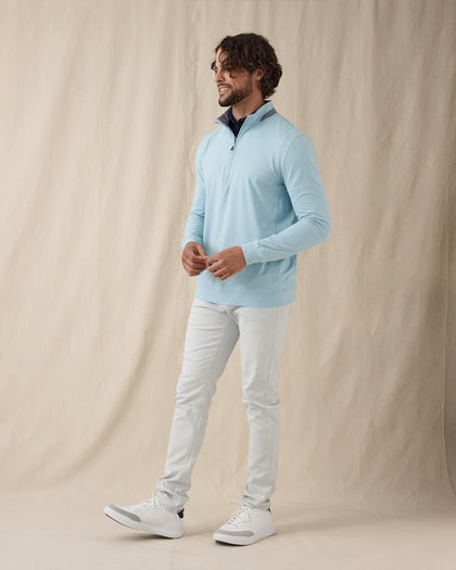 Men's Cimarron Quarter Zip in Delphinium, full-length side view on male model in soft sky blue styled with white pants and white golf shoes against a neutral linen backdrop